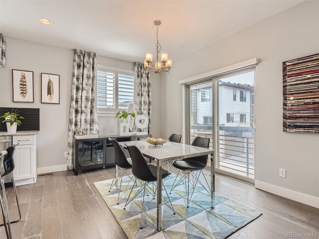 dining space with an inviting chandelier and light hardwood / wood-style flooring