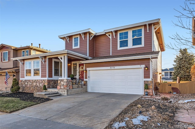 view of front facade featuring a garage, stone siding, fence, and driveway