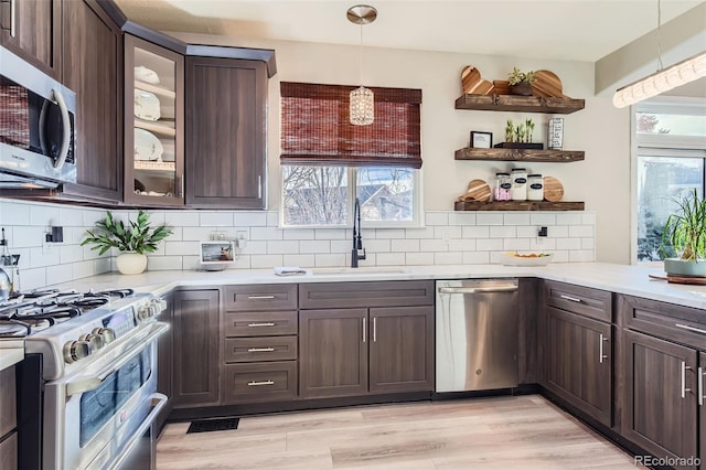 kitchen featuring dark brown cabinets, stainless steel appliances, a sink, and light countertops