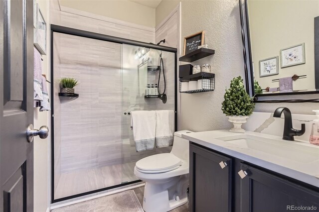 full bath featuring a textured wall, a shower stall, toilet, and vanity