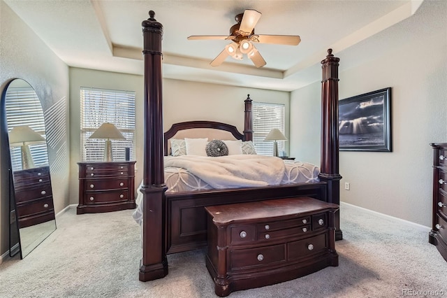 carpeted bedroom featuring baseboards, a raised ceiling, and a ceiling fan