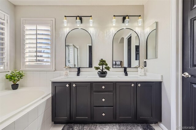 bathroom with a garden tub, double vanity, and a sink