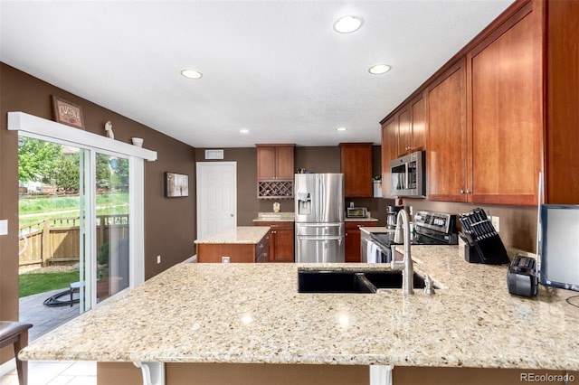 3505 Dinosaur St, Castle Rock, CO 80109 - kitchen featuring appliances with stainless steel finishes, recessed lighting, brown cabinets, a peninsula, and light stone counters