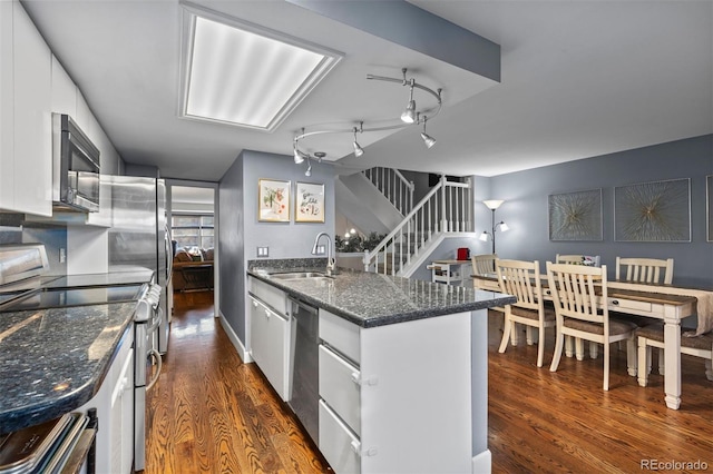 kitchen featuring white cabinetry, dark hardwood / wood-style flooring, stainless steel appliances, dark stone counters, and sink