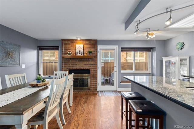 dining room with a brick fireplace and wood-type flooring