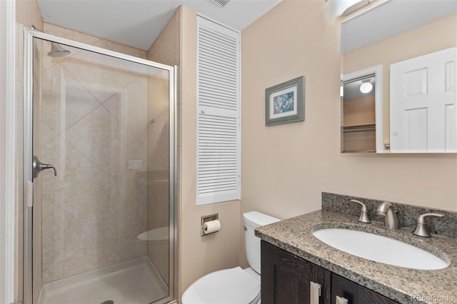 bathroom featuring toilet, vanity, and a shower with door