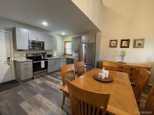 kitchen featuring dark wood-type flooring, appliances with stainless steel finishes, gray cabinets, and sink