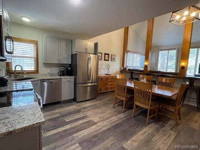 kitchen with gray cabinets, light stone countertops, appliances with stainless steel finishes, and dark wood-type flooring