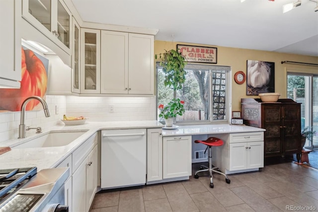 kitchen featuring light tile patterned flooring, sink, white cabinetry, white dishwasher, and decorative backsplash