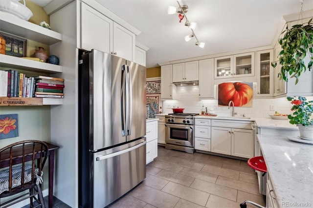 kitchen featuring sink, appliances with stainless steel finishes, tasteful backsplash, light stone countertops, and white cabinets