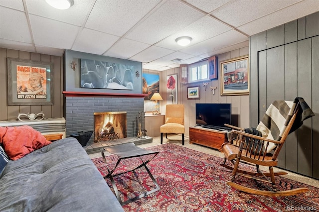 living room featuring a brick fireplace and a paneled ceiling