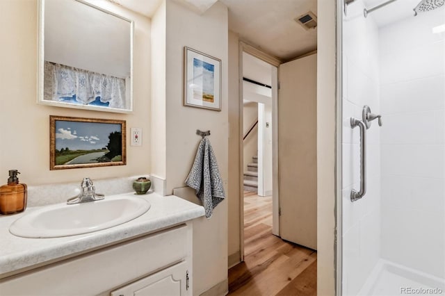 bathroom with hardwood / wood-style flooring, vanity, and a shower