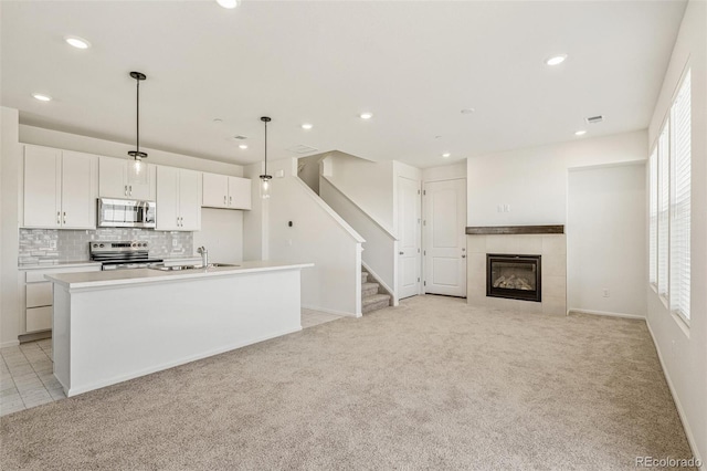 13458 E 111th Ave, Commerce City, CO 80022 - kitchen featuring stainless steel appliances, a sink, light carpet, a kitchen island with sink, and white cabinets