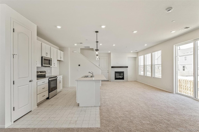 13458 E 111th Ave, Commerce City, CO 80022 - kitchen featuring appliances with stainless steel finishes, a sink, white cabinetry, a glass covered fireplace, and light countertops