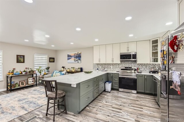 7465 S Ivy Way, Centennial, CO 80112 - kitchen with appliances with stainless steel finishes, gray cabinets, a peninsula, a kitchen breakfast bar, and white cabinetry