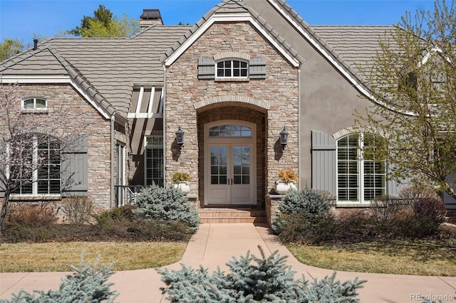 property entrance with stone siding, a tiled roof, and stucco siding