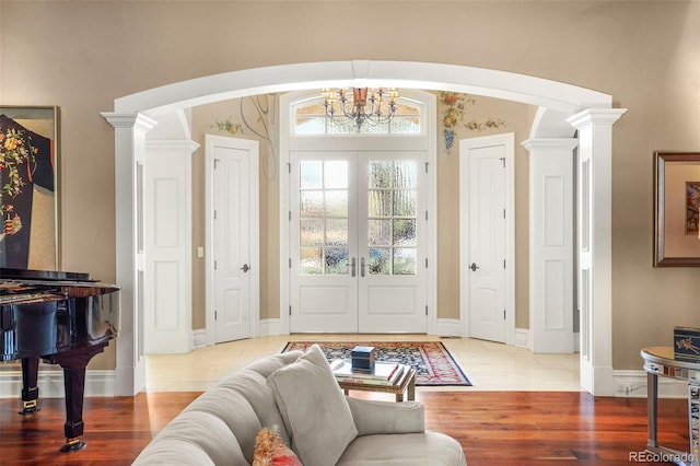 foyer entrance featuring an inviting chandelier, decorative columns, wood finished floors, and arched walkways