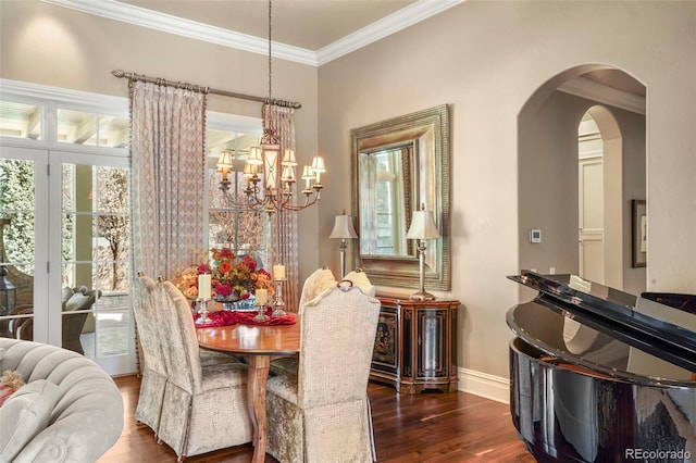 dining room with ornamental molding, baseboards, a notable chandelier, and wood finished floors