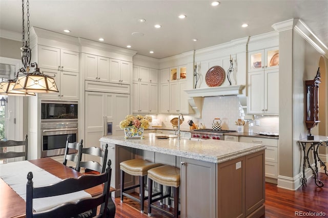 kitchen featuring stainless steel oven, dark wood-style flooring, a center island with sink, and built in microwave