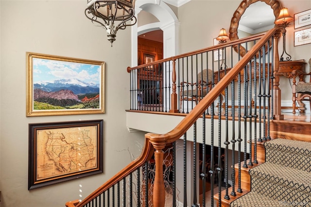 stairs featuring arched walkways, wood finished floors, crown molding, and ornate columns