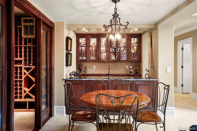 bar with decorative light fixtures, baseboards, a notable chandelier, and wet bar