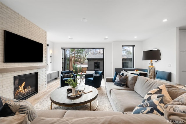 living room featuring a fireplace, light wood-style flooring, a wealth of natural light, and recessed lighting