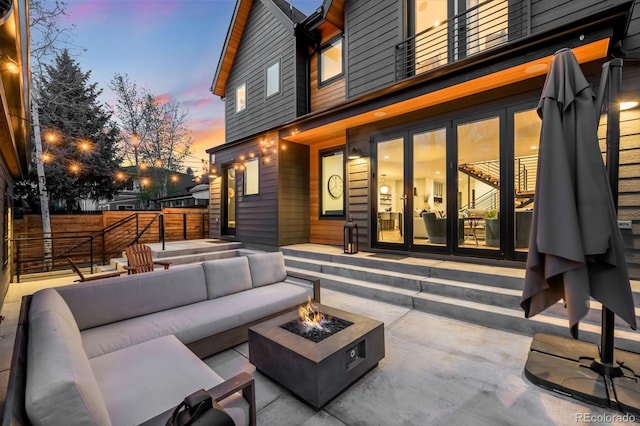 view of patio with an outdoor living space with a fire pit, fence, and a balcony