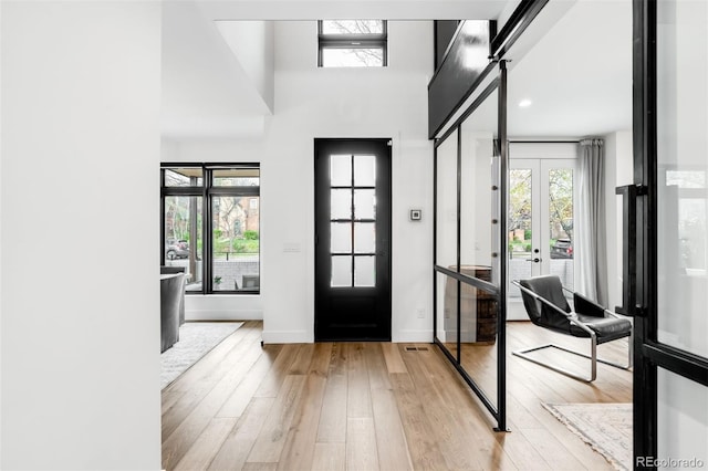 entrance foyer with baseboards, french doors, and light wood-style flooring