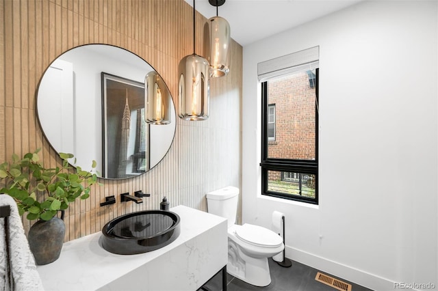 bathroom featuring a sink, toilet, plenty of natural light, and visible vents