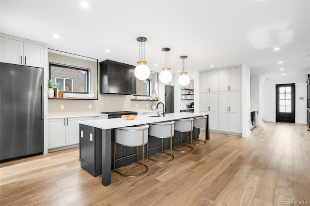 kitchen featuring a sink, stainless steel refrigerator, recessed lighting, light countertops, and decorative backsplash