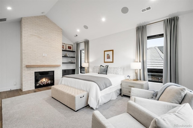 bedroom with high vaulted ceiling, a brick fireplace, visible vents, and wood finished floors