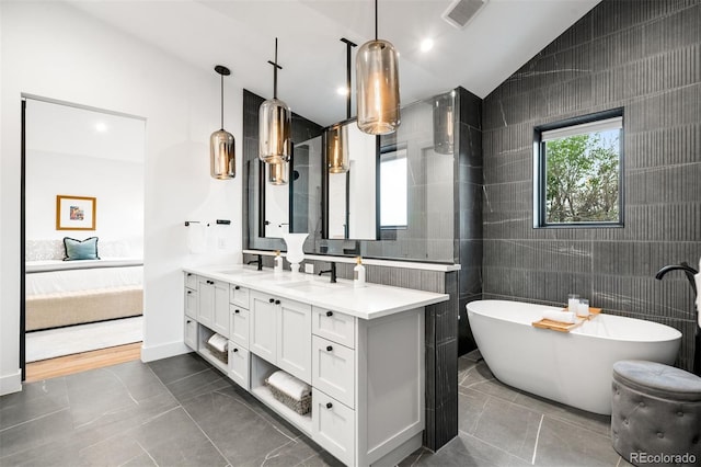 ensuite bathroom with double vanity, tile walls, visible vents, and a sink