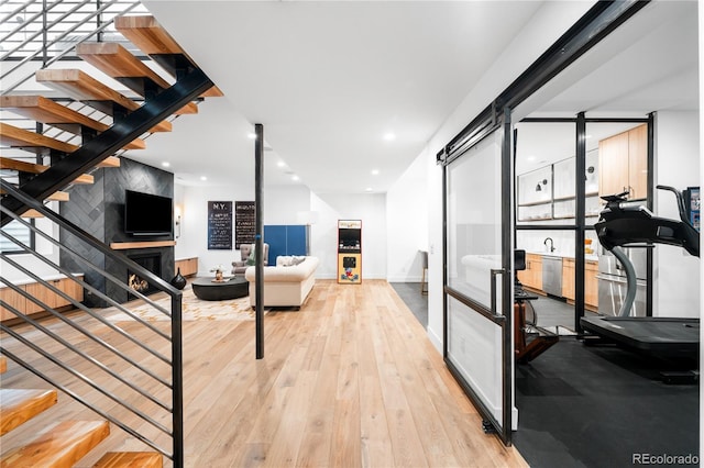 interior space featuring a large fireplace, stairs, wood-type flooring, and baseboards