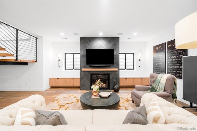 living area with a large fireplace, wood finished floors, baseboards, and recessed lighting