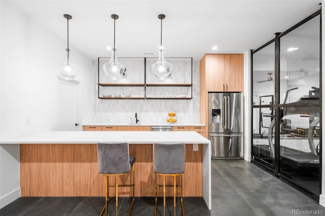 kitchen with a sink, a peninsula, a breakfast bar area, light countertops, and appliances with stainless steel finishes