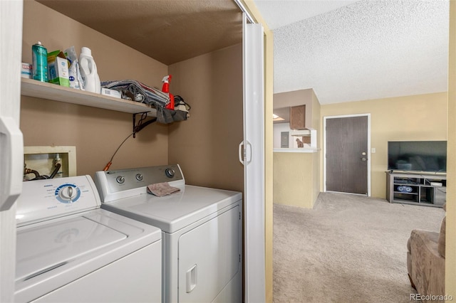 laundry room with light colored carpet, washing machine and dryer, and a textured ceiling