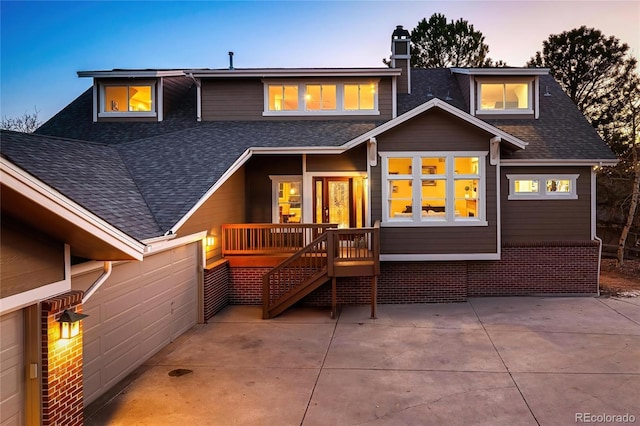 back of property at dusk featuring a patio, roof with shingles, and a chimney