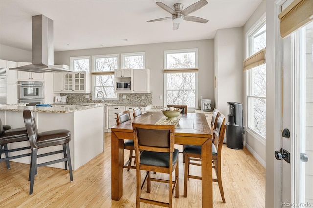 dining room featuring light wood-style flooring, baseboards, and a ceiling fan