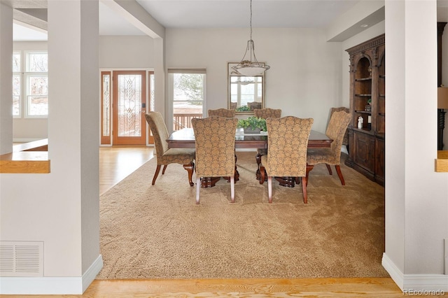 dining space featuring wood finished floors, baseboards, and visible vents