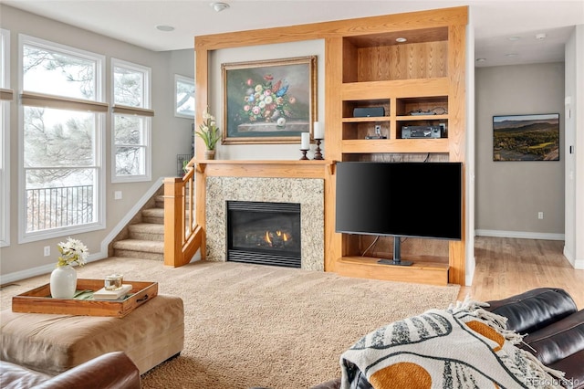 living room featuring built in shelves, baseboards, stairway, a fireplace, and wood finished floors