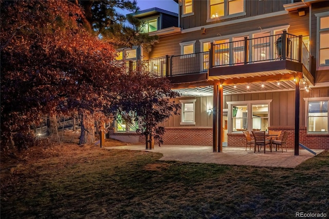 back of house featuring brick siding, board and batten siding, and a patio area