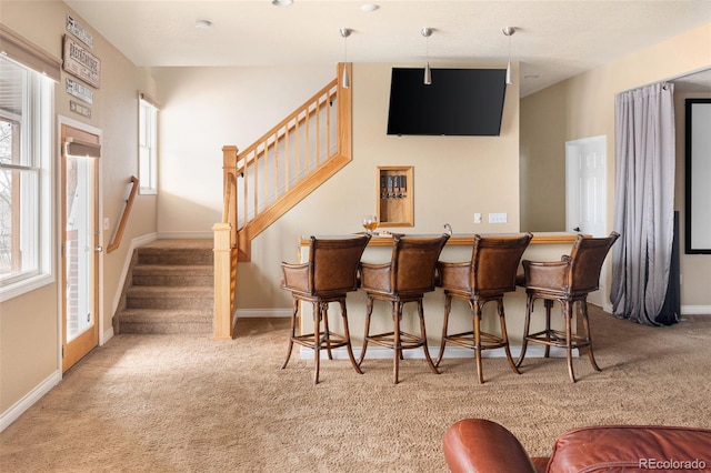 bar featuring stairway, wet bar, baseboards, and carpet floors