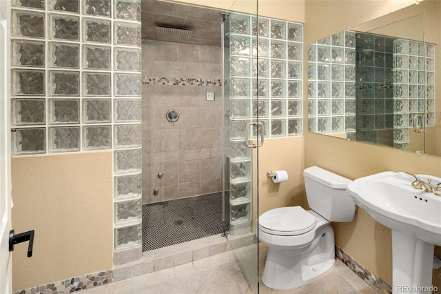 bathroom with tile patterned floors, toilet, a sink, and a walk in shower