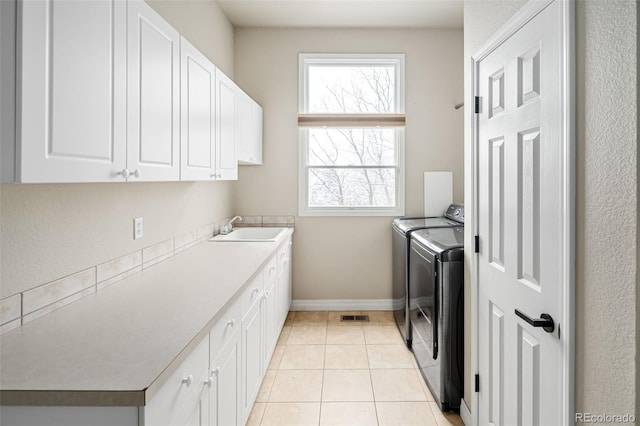 washroom featuring baseboards, washing machine and dryer, light tile patterned floors, cabinet space, and a sink