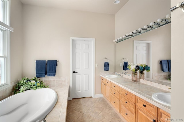 full bath with a sink, tiled tub, double vanity, and tile patterned flooring