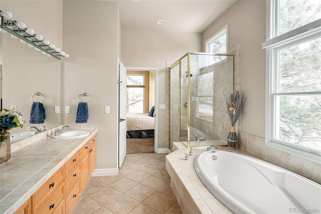 ensuite bathroom featuring double vanity, a bath, connected bathroom, and a sink