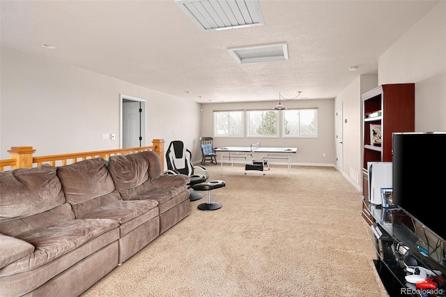 living area with carpet flooring, attic access, a textured ceiling, and baseboards