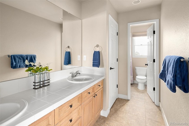 bathroom featuring toilet, a sink, tile patterned flooring, double vanity, and baseboards