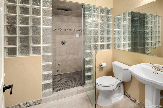 bathroom with tile patterned floors, toilet, a walk in shower, and a sink