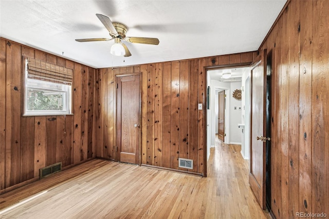 4285 Newland St, Wheat Ridge, CO 80033 - unfurnished bedroom with wood walls, light wood-style flooring, baseboards, and a ceiling fan